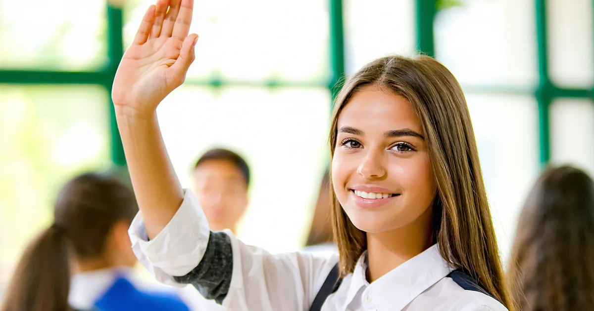 A student raising their hand confidently in a well-lit classroom setting